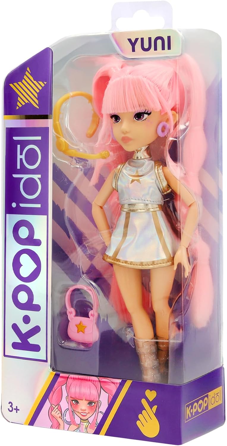 Bambola K-Pop Idol Yuni IMC Toys nella confezione, con capelli rosa intrecciati, outfit argentato iridescente e borsetta rosa.