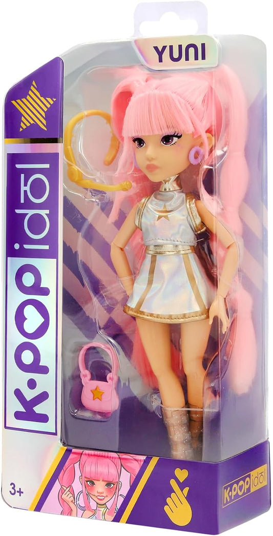 Bambola K-Pop Idol Yuni IMC Toys nella confezione, con capelli rosa intrecciati, outfit argentato iridescente e borsetta rosa.