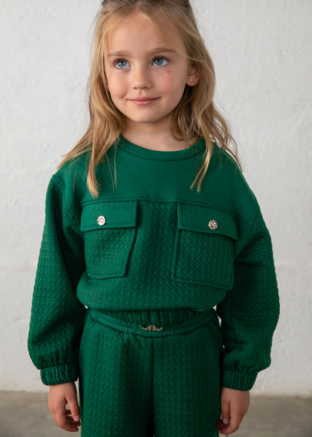 Dettaglio del completo bambina Mayoral verde bottiglia con tasche decorative e bottoni metallici