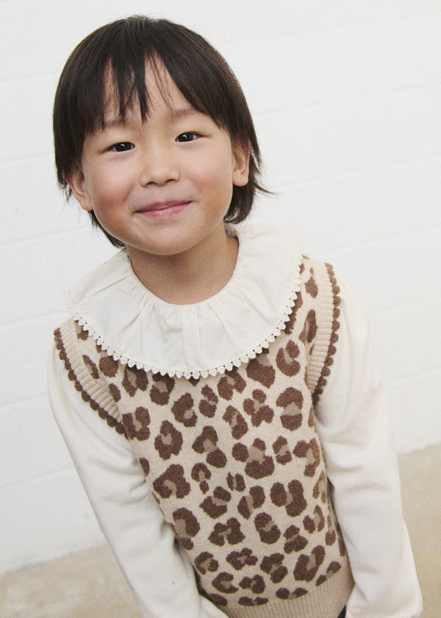 Gilet bambina Mayoral animalier beige e marrone indossato sopra una camicia bianca